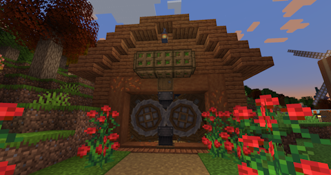 a wooden building fronted by roses houses a pair of large stone crushing wheels